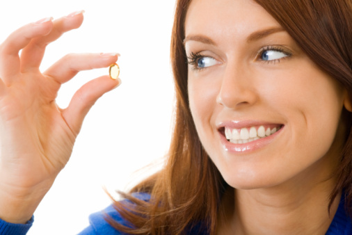 Young happy woman with Omega 3 fish oil capsula, isolated